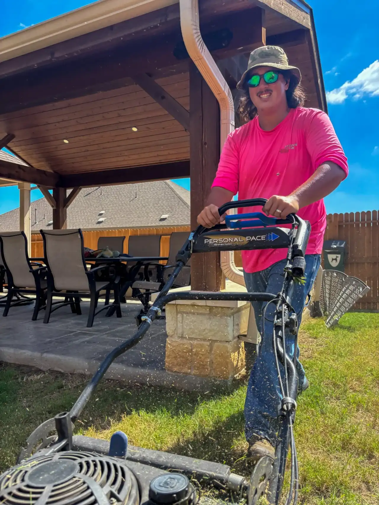 Lemonade Lawn Care technician mowing a backyard lawn in New Braunfels with a push mower